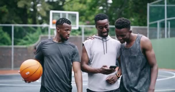 Mustat ihmiset, älypuhelin ja nauraa koripallokenttä urheilu ja liikunta ulkona terveydelle. Afrikkalainen urheilija, vitsi ja sosiaalinen media koulutukseen hyvinvointi, mobiilisovellus ja aktiivinen luonteeltaan. - Materiaali, video