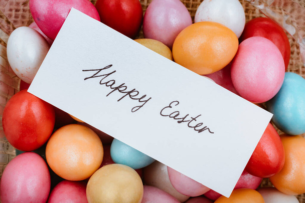 Renkli dekoratif taşlar üzerine küçük bir kağıda yazılmış Paskalyanız kutlu olsun. - Fotoğraf, Görsel