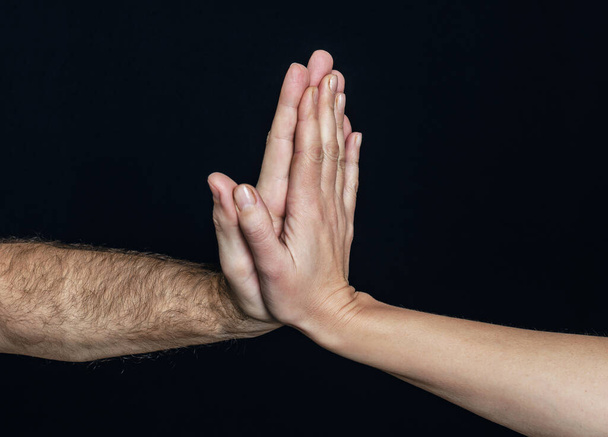 Αρσενικά και θηλυκά χέρια παλαμάκια μαζί σε μαύρο φόντο - Φωτογραφία, εικόνα