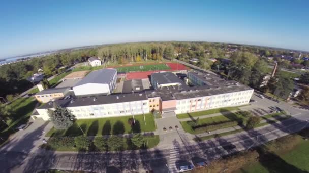 Luftaufnahme des Schulgeländes mit Blick auf das Fußballfeld von oben in der Mitte eines kleinen Dorfes - Filmmaterial, Video