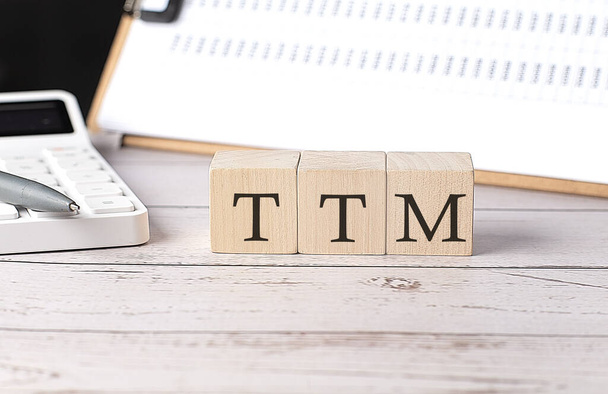 Слово TTM на деревянном блоке с буфером обмена и калькулятором - Фото, изображение