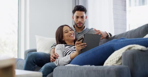 Paar, Tablet und Kreditkarte für Online-Einkäufe mit Lachen, Gespräch und Glück im Liegen auf dem Sofa. Mann, Frau und Internet-Bezahlung mit Technologie, entspannt und glücklich auf der Couch der Lounge. - Filmmaterial, Video