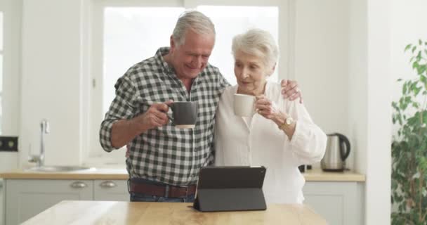Šťastný pár, senior a káva s tabletem doma pro zábavu, internet nebo streaming online. Starší muž, žena a technika pro informace, výzkum nebo prohlížení v kuchyni s teplým nápojem. - Záběry, video