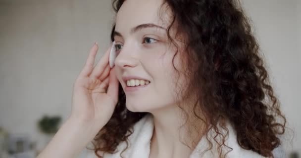 Young brunette woman removing makeup from her face with cotton pad. Body care. female model with facial pad to remove makeup cosmetics for healthy skin and cleaning. Love yourself. - Footage, Video
