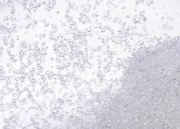 Κοντινό πλάνο της κρυσταλλικής ζάχαρης σε γυάλινα μπουκάλια σε λευκό φόντο. - Φωτογραφία, εικόνα
