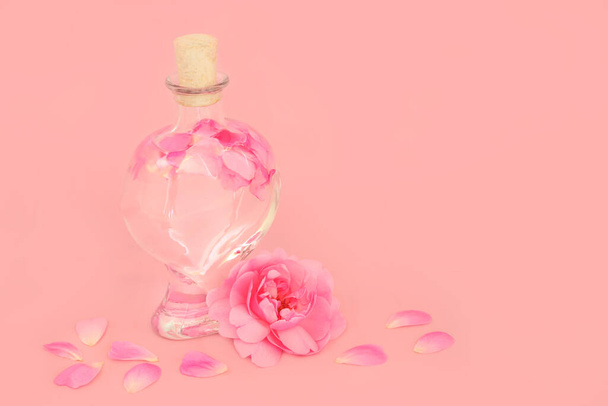 Rose perfume flor em forma de coração garrafa com pétalas soltas em rosa. Produto de beleza floral puro natural, presente para o dia dos namorados, aniversário, aniversário ou dia das mães. - Foto, Imagem