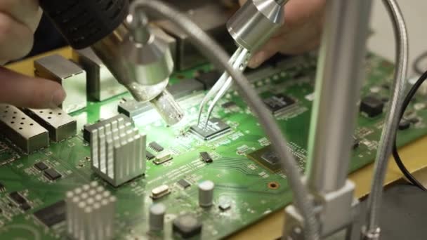 Macro, egy férfi közelről megjavítja a chipet egy forrasztópákával. Elektronikus áramköri lapot forrasztópákával javító mérnök vagy technikus. Elektronikai javítás 4K - Felvétel, videó