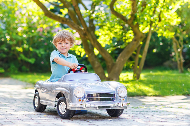 小さな男の子の屋外の大きなおもちゃの古い車を運転 - 写真・画像