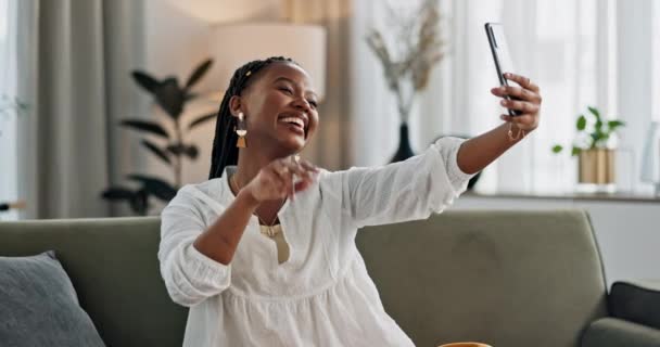 Smile, selfie and black woman with peace sign, funny face and relax on sofa in living room. V hand, picture and happy African person or influencer at home on couch on social media with tongue out. - Footage, Video