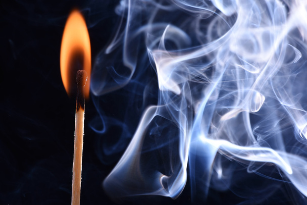 Fósforo quemado en un humo sobre un fondo negro. El humo de cian sale de un fósforo extinguido. fuego fuego fuego partido y partido ahumado
 - Foto, imagen