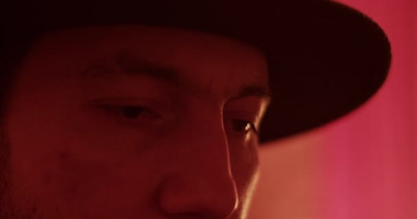 Hombre adulto serio con sombrero negro mirando hacia abajo durante las huelgas de iluminación en casa - Metraje, vídeo