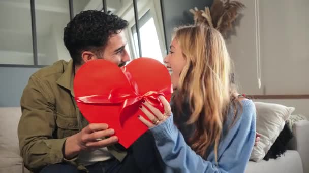 Vriendje omarmen en geven zijn vriendin een hartvormig kistje cadeau om Valentijnsdag te vieren. Jong stel met een verrassing aanwezig op hun relatie verjaardag. Liefde en romantiek. Hoog - Video
