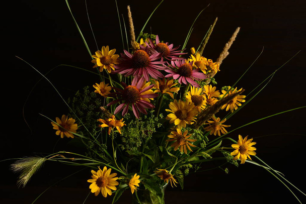 Bukiet kwiatów zebranych w dziczy w prostym szklanym wazonie Izolowanym na czarnym tle. - Zdjęcie, obraz