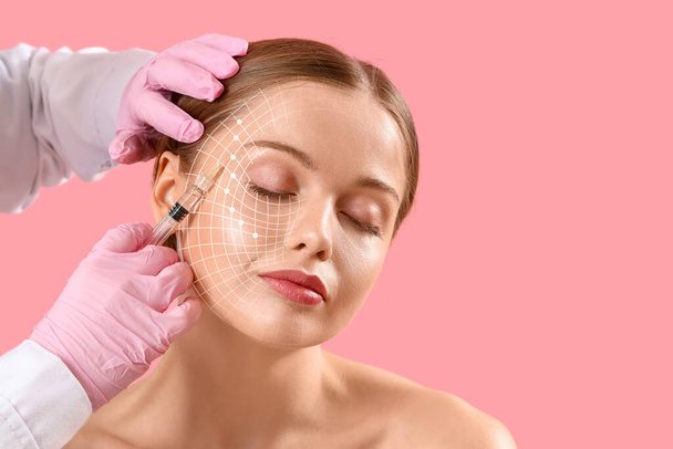 Young woman receiving filler injection in face against pink background  - Photo, Image
