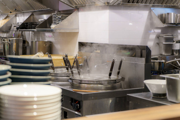Bustling cocina de un restaurante de ramen caldo de vapor para tallarines hábilmente elaborados, esta escena encarna el dominio culinario y la dedicación a los sabores auténticos - Foto, imagen