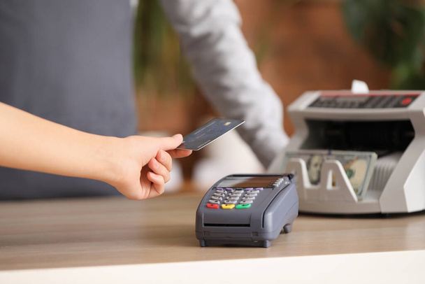 Jonge vrouw betaalt met credit card via bankterminal in de winkel, close-up - Foto, afbeelding