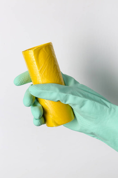 Hand in rubber glove with roll of garbage bags on white background - Photo, Image