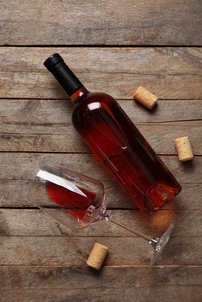 Glas en fles rode wijn op houten ondergrond - Foto, afbeelding