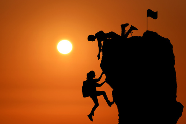 Le travail d'équipe conjoint de deux personnes hommes et filles voyageurs s'entraident au sommet d'une équipe d'alpinisme, un magnifique paysage de coucher de soleil
. - Photo, image