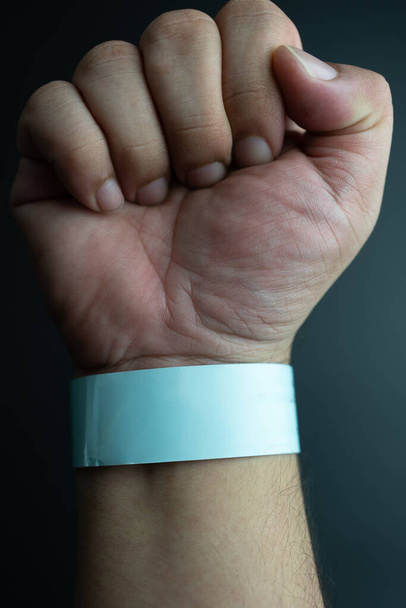 Blue paper wristband mockup on persons arm. Empty adhesive bangle wristlet sticker on male hand, blue paper bracelet, check tape, event ticket concept - 写真・画像