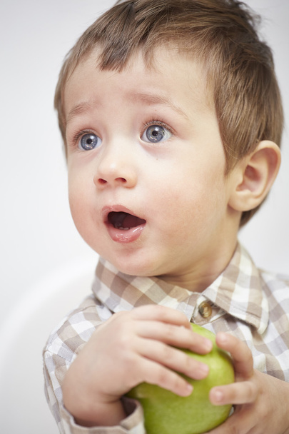 Little boy with an apple looking surprised - Фото, зображення