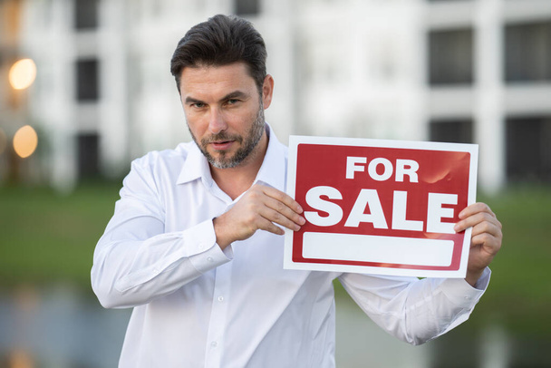 a man in a white shirt holding money in his hands. real state agent giving new house key. Estate agent with customer before contract signature. male real state agent with a for sale or rent sign. - Photo, Image