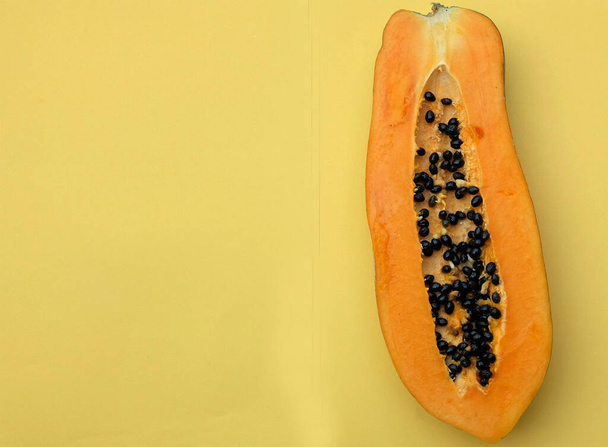 top view and flat lay a sweet ripe papaya fruit papaya with slice isolated on a yellow backdrop. vegetable and fruit for healthy nutrition.vegan food - Photo, Image