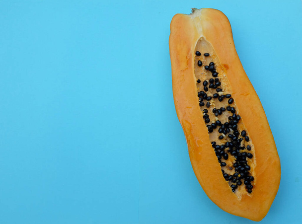 Üst ve düz bir zemin üzerinde tatlı olgun papaya meyveli papaya ve dilimlenmiş mavi bir zemin uzanıyor. Sağlıklı beslenme için sebze ve meyve. - Fotoğraf, Görsel