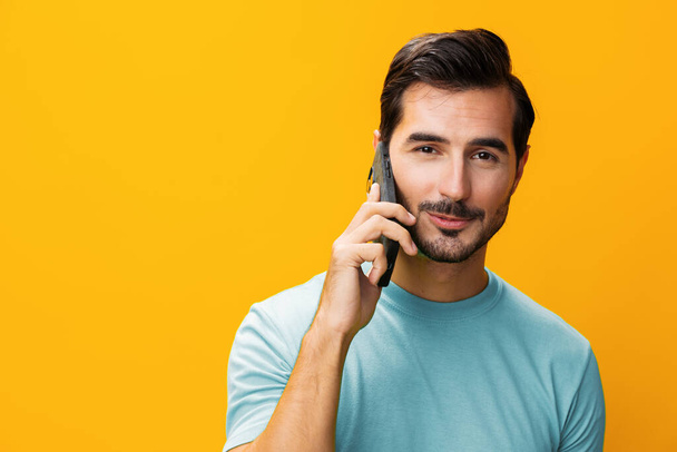 Communication man portrait message toothy technology eyeglass studio mobile lifestyle cyberspace smile phone yellow pointing business copy phone surprise space smartphone happy smiling - Photo, Image