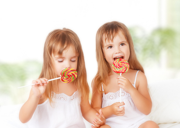 glückliches Mädchen Zwillingsschwestern mit Lutschern Süßigkeiten - Foto, Bild
