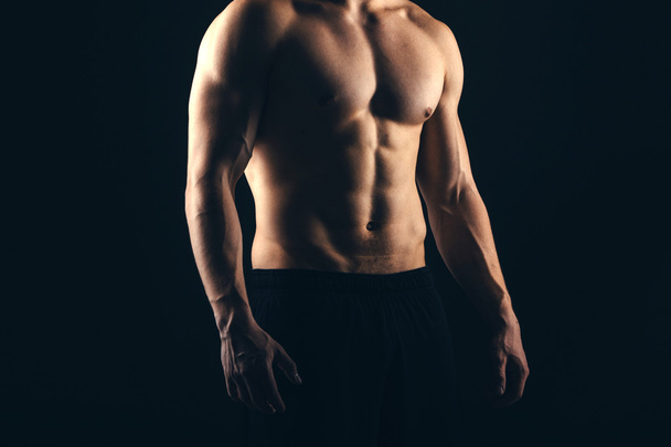 Close up of sports mans muscular isolated on black background - Zdjęcie, obraz