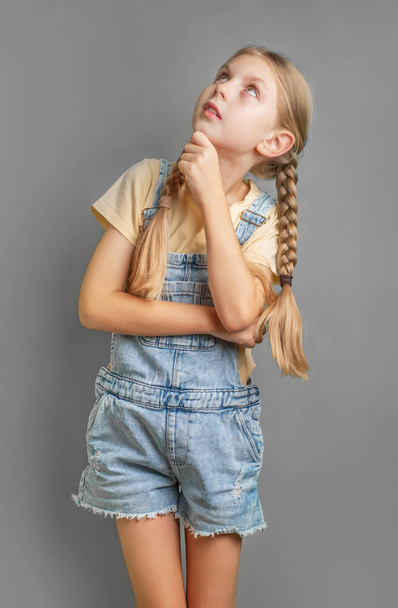 Retrato de una niña con el pelo trenzado que está pensando y mirando hacia arriba - Foto, imagen