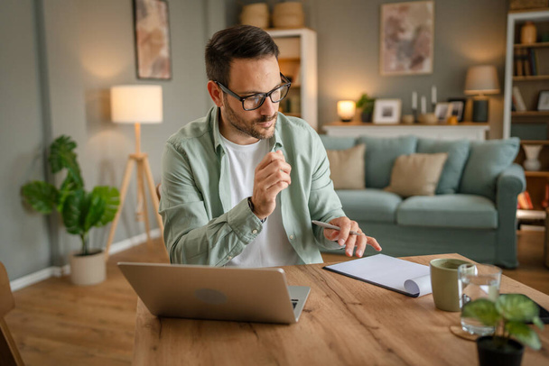een man volwassen blanke man met baard werk op zijn laptop computer thuis op te lossen probleem freelance ondernemer of remote werk concept - Foto, afbeelding