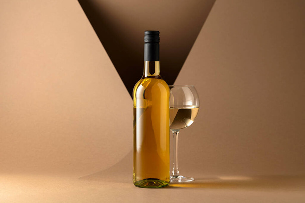 Bottle and glass of white wine on a beige background. Copy space. - Zdjęcie, obraz
