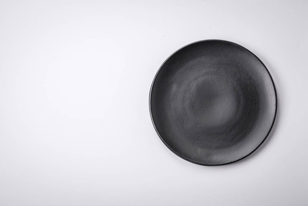 Порожня кругла керамічна тарілка на звичайному фоні, плоска з простором для копіювання. Кухонне начиння на домашній кухні - Фото, зображення