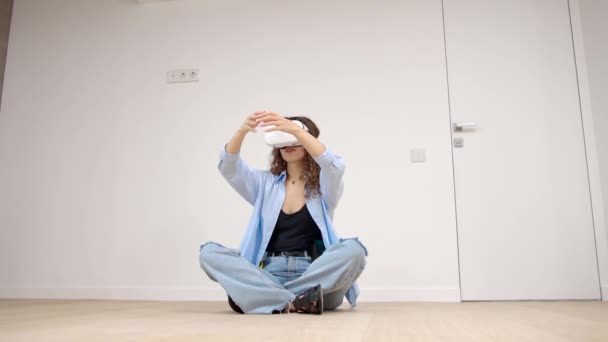 Egy tinédzser lány virtuális valóság szemüvegben vagy 3D-s szemüvegben ül egy szobában. Az emberek szórakoztatása. Technológia, virtuális valóság, kibertér - Felvétel, videó