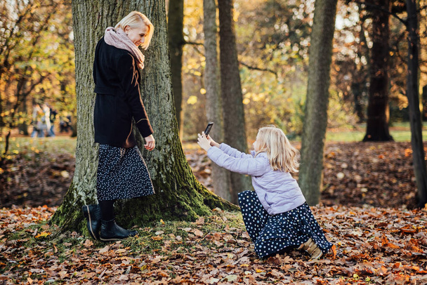 Ebeveyn-çocuk bağı ve anne-kız ilişkileri. Anne ve kızı kucaklıyor, sonbaharın altın renkleri arasında özel bir selfie çekiyorlar. - Fotoğraf, Görsel