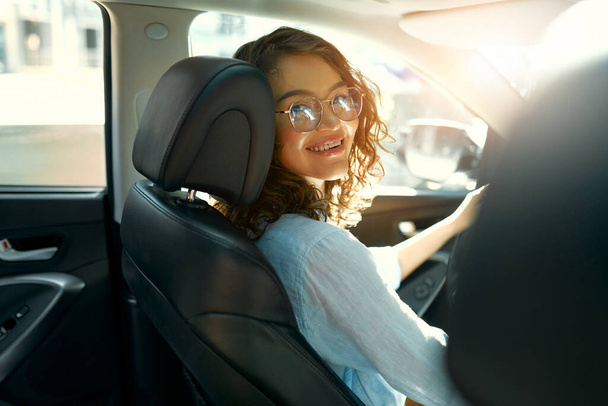 Krásná mladá šťastná usměvavá žena řídí své nové auto. Kupuje a pronajímá auto. Cestování, cestovní ruch, rekreace. - Fotografie, Obrázek