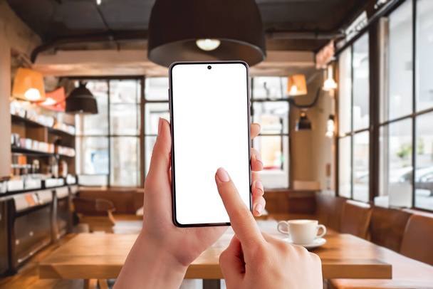 Bir kafede akıllı telefon modeli, verimli bir sabahın özünü yakalıyor. Moda kafe ortamında mobil konsept üzerine çalışmanın gösterimi için ideal - Fotoğraf, Görsel