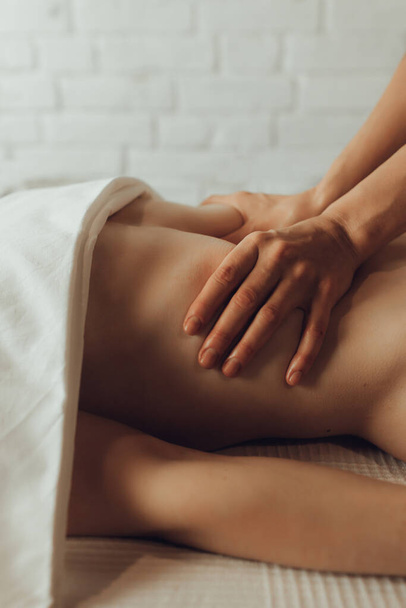 Ruce ženského chiropraktika masírujícího břicho mladé ženy ležící na masážním stole na bílém pozadí. Viscerální masáž. Koncepce léčby fyzikální terapie, tlakový bod krku. - Fotografie, Obrázek