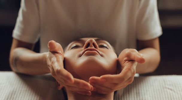 Руки жінки хіропрактика масажу обличчя молодої жінки лежать на масажному столі. Вісцеральний масаж. Концепція лікування фізичної терапії, точка тиску шиї. - Фото, зображення