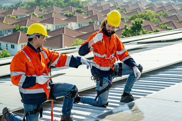Επαγγελματίες μηχανικοί ελέγχουν την ηλιακή οροφή του εργοστασίου κάτω από το φως του ήλιου. Μηχανικοί με εργασίες συντήρησης ηλεκτρικής ανανεώσιμης οικολογικής ενέργειας - Φωτογραφία, εικόνα