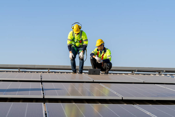 Ingegneri professionisti che controllano il tetto solare sul tetto della fabbrica sotto la luce solare. Ingegneri che svolgono attività di servizio di energia elettrica rinnovabile - Foto, immagini