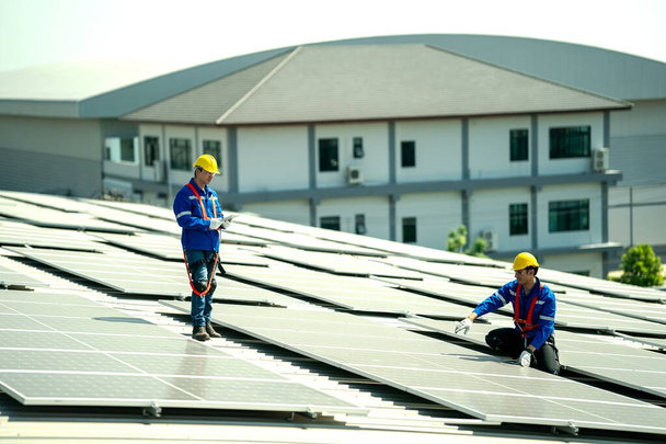 日光の下で工場屋上に太陽の屋根を点検する専門エンジニア. 電気再生可能エネルギーのサービスジョブを持っているエンジニア - 写真・画像