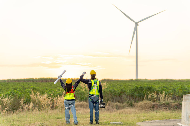 Два багаторасові промислові працівники вивчають вітрові турбіни. Сільська місцевість з екологічною фермою виробництва екологічно чистої зеленої енергії - Фото, зображення