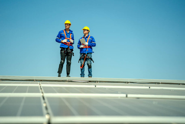 Ammattimaiset insinöörit tarkistavat aurinkokaton tehtaan katolla auringonvalon alla. Insinöörit, jotka hoitavat uusiutuvan sähköenergian huoltotöitä - Valokuva, kuva