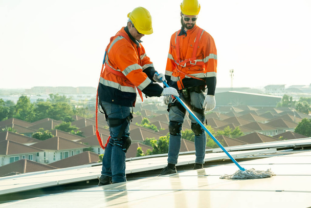 Επαγγελματίες μηχανικοί ελέγχουν την ηλιακή οροφή του εργοστασίου κάτω από το φως του ήλιου. Μηχανικοί με εργασίες συντήρησης ηλεκτρικής ανανεώσιμης οικολογικής ενέργειας - Φωτογραφία, εικόνα