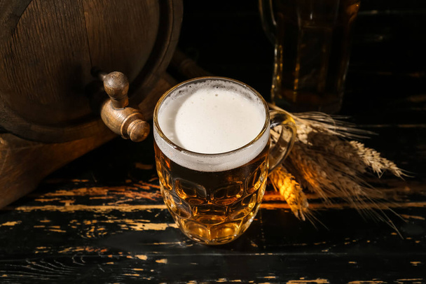 Kubek zimnego piwa i dębowej beczki na ciemnym drewnianym tle - Zdjęcie, obraz
