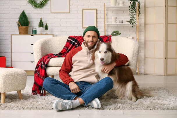 クリスマスイブに自宅でかわいいハスキー犬とハンサムな若い男 - 写真・画像