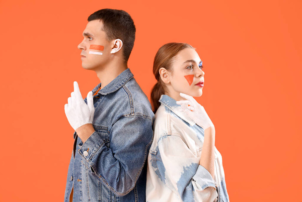 Jeune couple avec des visages peints sur fond orange - Photo, image